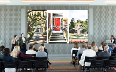 A group of people seated facing a projected image of three artworks displayed on a screen, representing the Roots, Soul, and Flair palettes of the Colors of Savannah project, with presenters standing nearby.