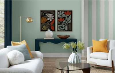 Living room painted in SW 6456 Slow Green with neutral couch, throw pillows, side tables, and decor.