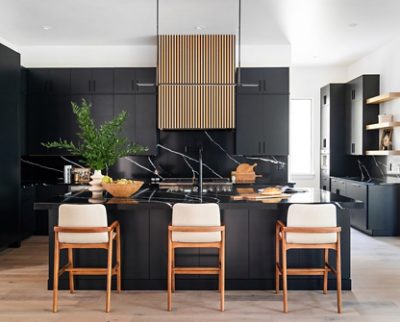 Modern kitchen with Tricorn Black cabinetry, Pure White ceiling, marble island, wooden barstools, and a vertical slatted hood.