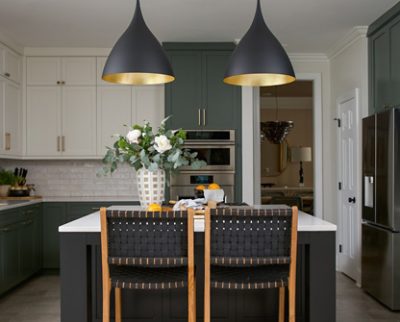 Modern kitchen with a central island painted Caviar by Sherwin-Williams, pendant lights, Pewter Green and Greek Villa cabinets, Drift of Mist walls, and a vase with flowers. 