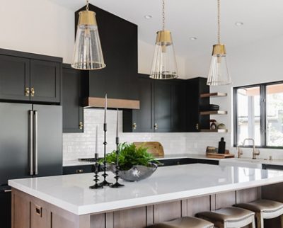 Modern kitchen with black cabinets, white marble island, and pendant lighting.