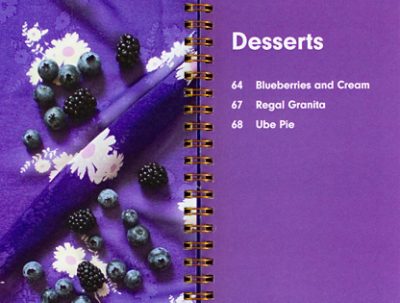 Spread from The Taste Curators purple-focused cookbook, including an image of berries on a purple cloth backdrop alongside a list of desserts.