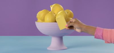 Lemon Twist SW 6909 color chip in front of a bowl of lemons.
