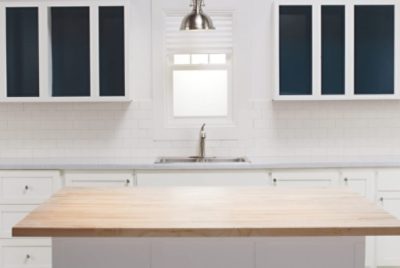 Modern kitchen with white cabinets, dark blue interiors, wooden island, and subway tile backsplash.
