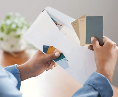 A person taking Sherwin-Williams color chips samples out of an envelope.