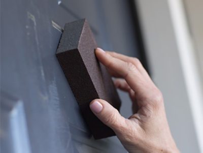 Person sanding a front door.