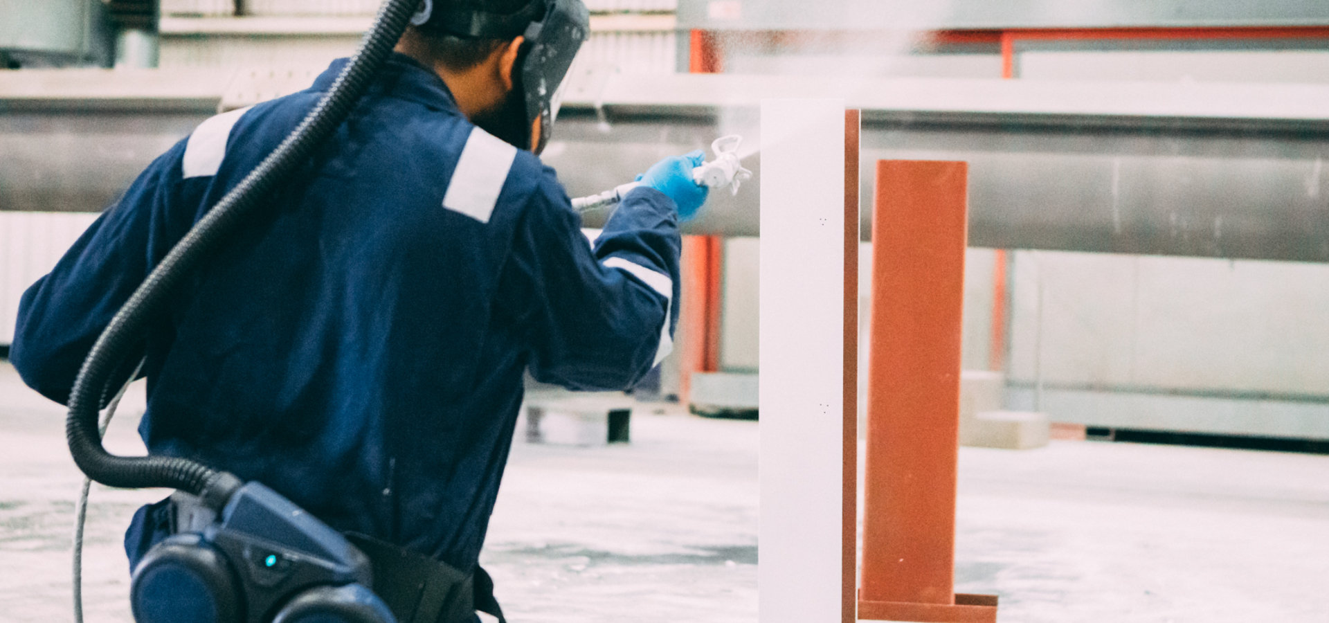 A man applies coating to a steel beam on a construction site