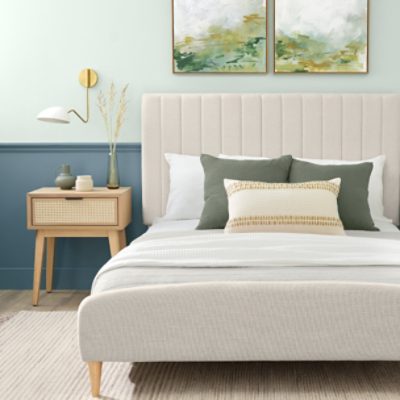 A bedroom with an upholstered bed against a wall painted green on the top half.
