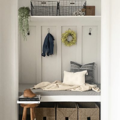 A home's hallway storage nook with a little bench, hooks, and storage bins.