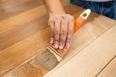 Applying stain to wood with a brush.