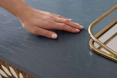 A person's hand on a blue stained table.
