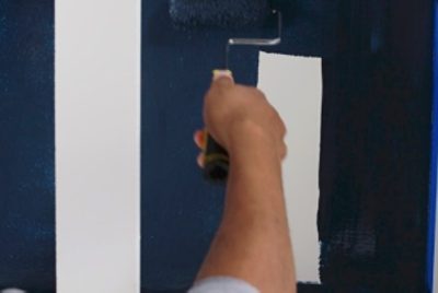 Using a mini-roller to paint the inside of the cabinet dark blue.