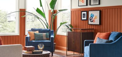 Living room with blue chairs and wood paneling in clay color.