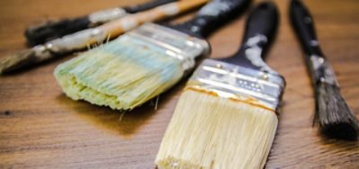 Various paint brushes laying on a wooden table.