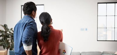 Two people standing together observing different paint samples on a wall.