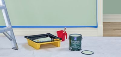 A photo of a room with paint supplies, including a ladder, one gallon of paint, and a paint tray with a paint roller.