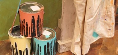 Paint cans stacked in a pyramid with paint drips down the side of each can.