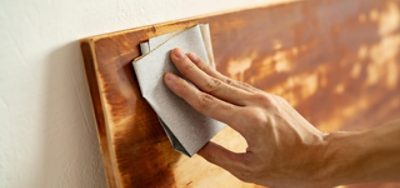 Sanding a piece of stained wood.