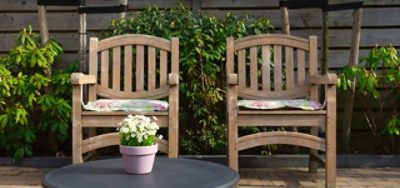 Two patio chairs in front of a flower bed.