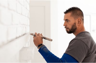 una persona pintando ladrillo blanco.