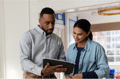 Two people standing and looking at a tablet.