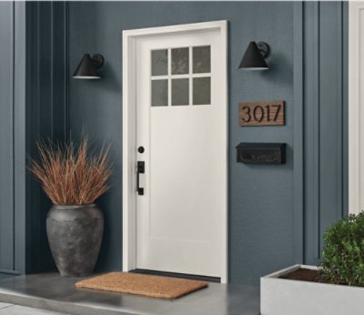 Entrance to a home with a white door, twin lamps and decorative vase.