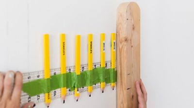 A person holding carpenter pencils, tape and a ruler. 