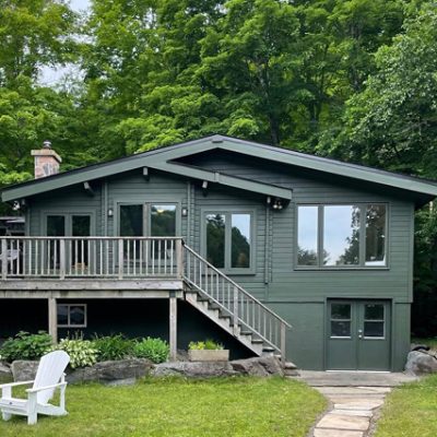 A dark green house in front of a forest. S-W featured color: SW 6994 Green Black. Photo credit @margotaustin.