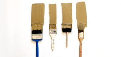 A set of four paint brushes with beige paint. 