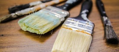 Various paint brushes laying on a wooden table.