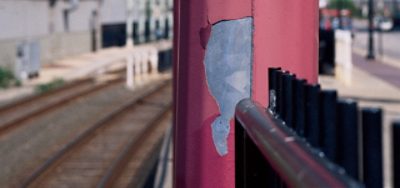 An exterior red post with peeling metal. 