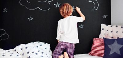 A child drawing on a chalkboard wall.