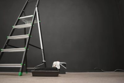 A finished chalkboard wall with a ladder and painting supplies on the floor.