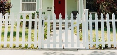 A white painted wooden fence in front of a house. 