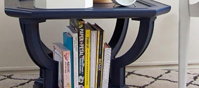 A dark blue end table with books and magazines. 