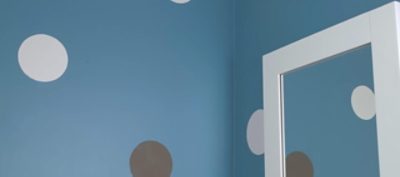 A room with bright blue paint and colorful polka dots. 