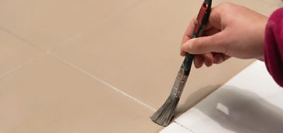 A person painting tile with a paint brush.