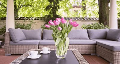 An outdoor sectional sofa on a stained deck.