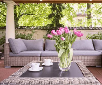 An outdoor sectional sofa on a stained deck.