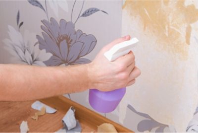 A person removing wallpaper using a fabric softener solution.