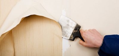 A person removing wallpaper.