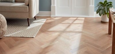 Light stained wood flooring in a room with tan furniture and light blue walls.