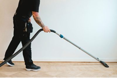 A person vacuuming the dust off wood floors after sanding.