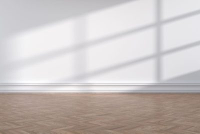 An empty room with wood floors and white walls.