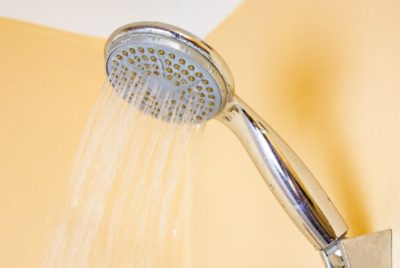 Close-up of a shower head with water running.