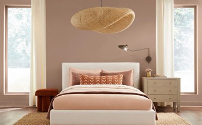 A bedroom with nude and orange bedding.