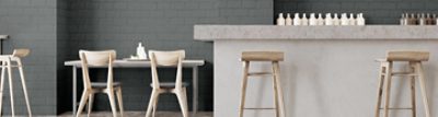 A modern kitchen with gray brick walls and concrete countertop.