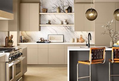 A kitchen with cream cabinets and wooden chairs.