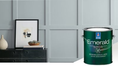A dark colored sideboard with a picture and vase against a bluish gray wall. Emerald interior acrylic latex.