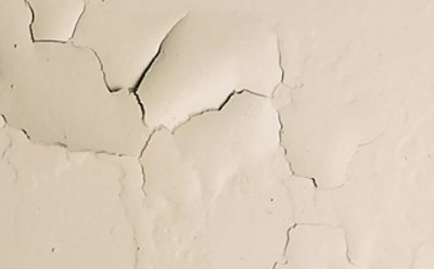 An interior white ceiling with paint cracks. 